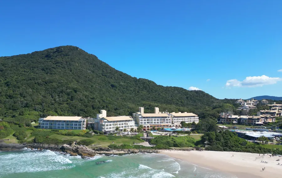 Resort Costão do Santinho visto do alto, entre o morro coberto de mata e a Praia do Santinho.